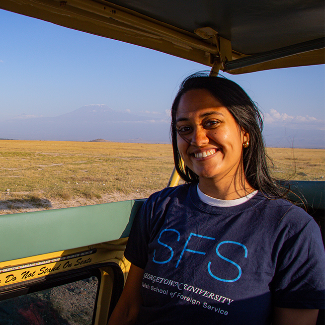 Woman smiling wearing an SFS tshirt. She is sitting in an open roof car, in an African safari